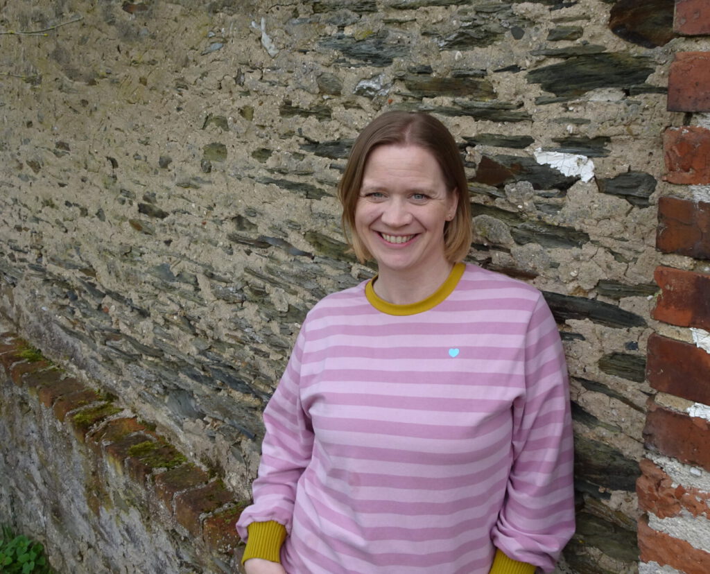 Portraitfoto von Familienberaterin Rebekka Krampitz vor einer Backsteinwand.